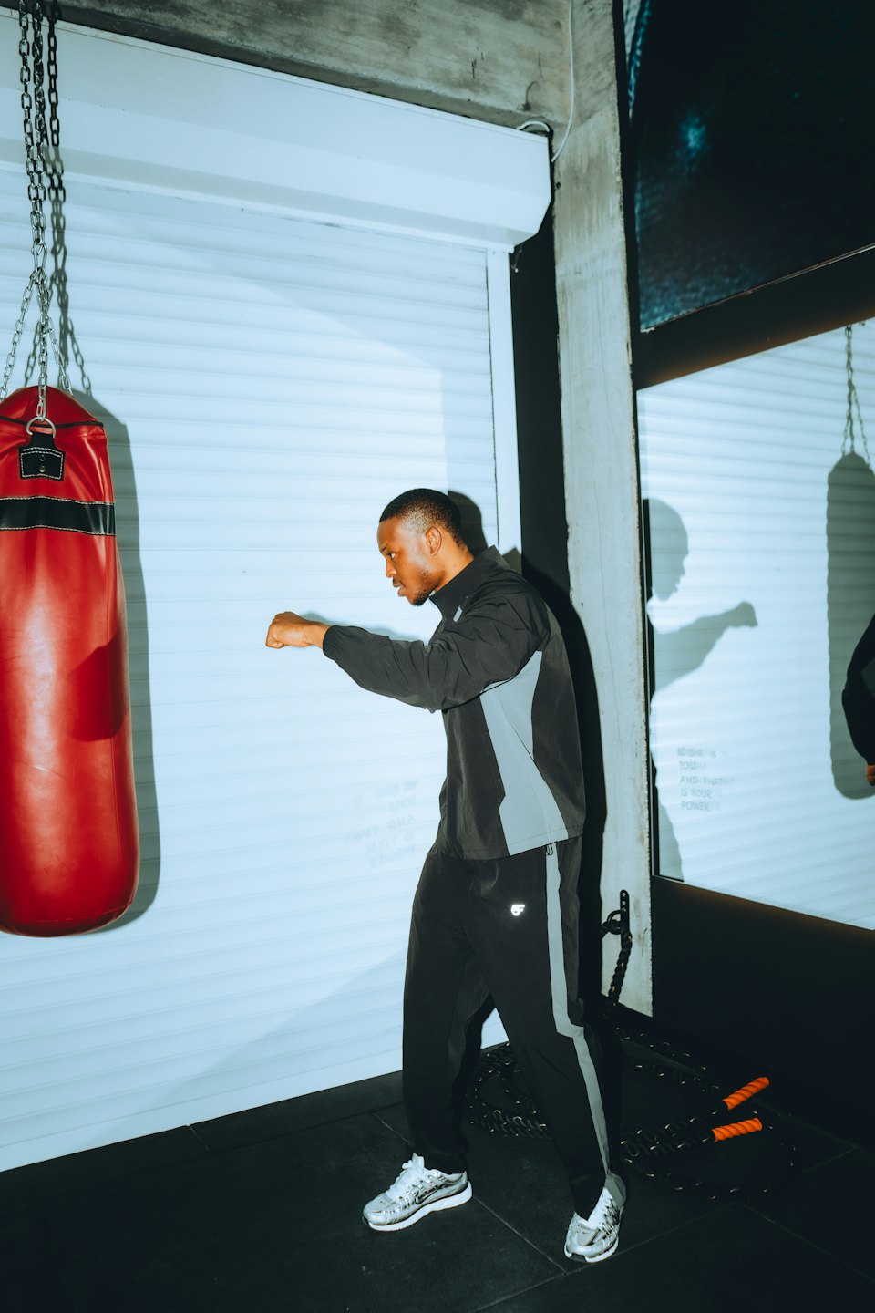 Boxer practicing punches on a hanging red punching bag.